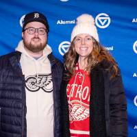 Couple standing in front of backdrop, posing for photo and smiling at camera